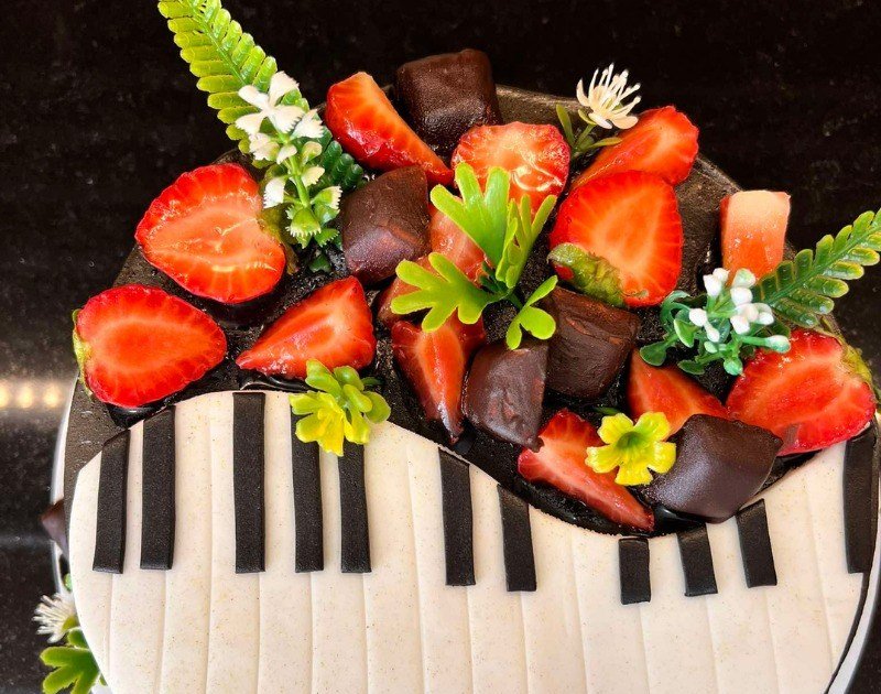 Bolo decorado com teclas de piano, morangos e chocolate